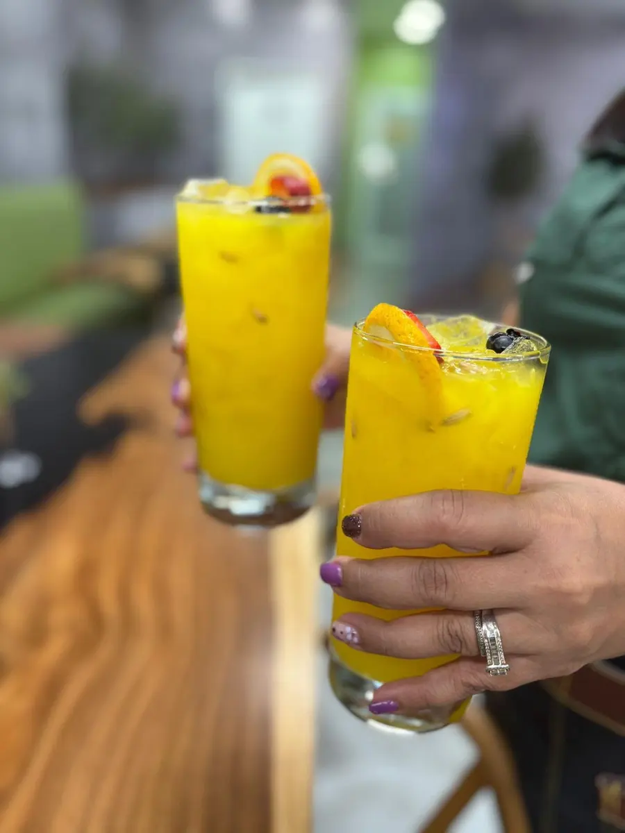 Dos bebidas de mango sostenidas en mano